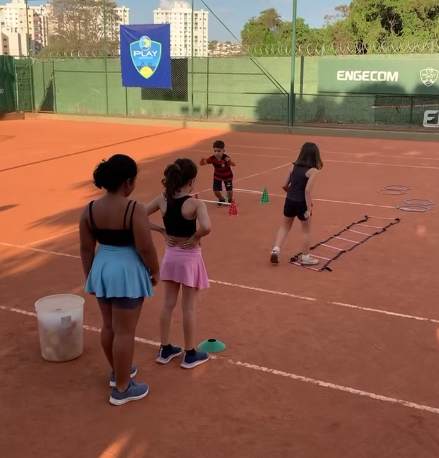Crianças treinando circuitos de agilidade na quadra de saibro da Play Anápolis